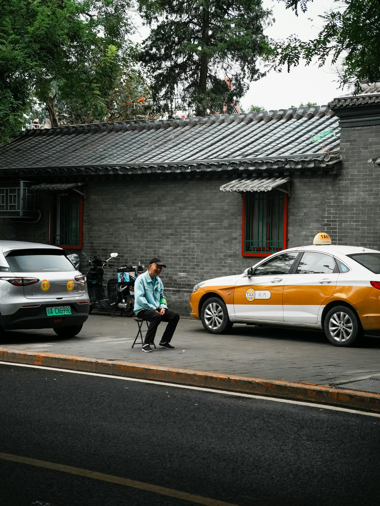 A yellow Beijing taxi on a city street, with Chinese and English signage on a meter visible inside