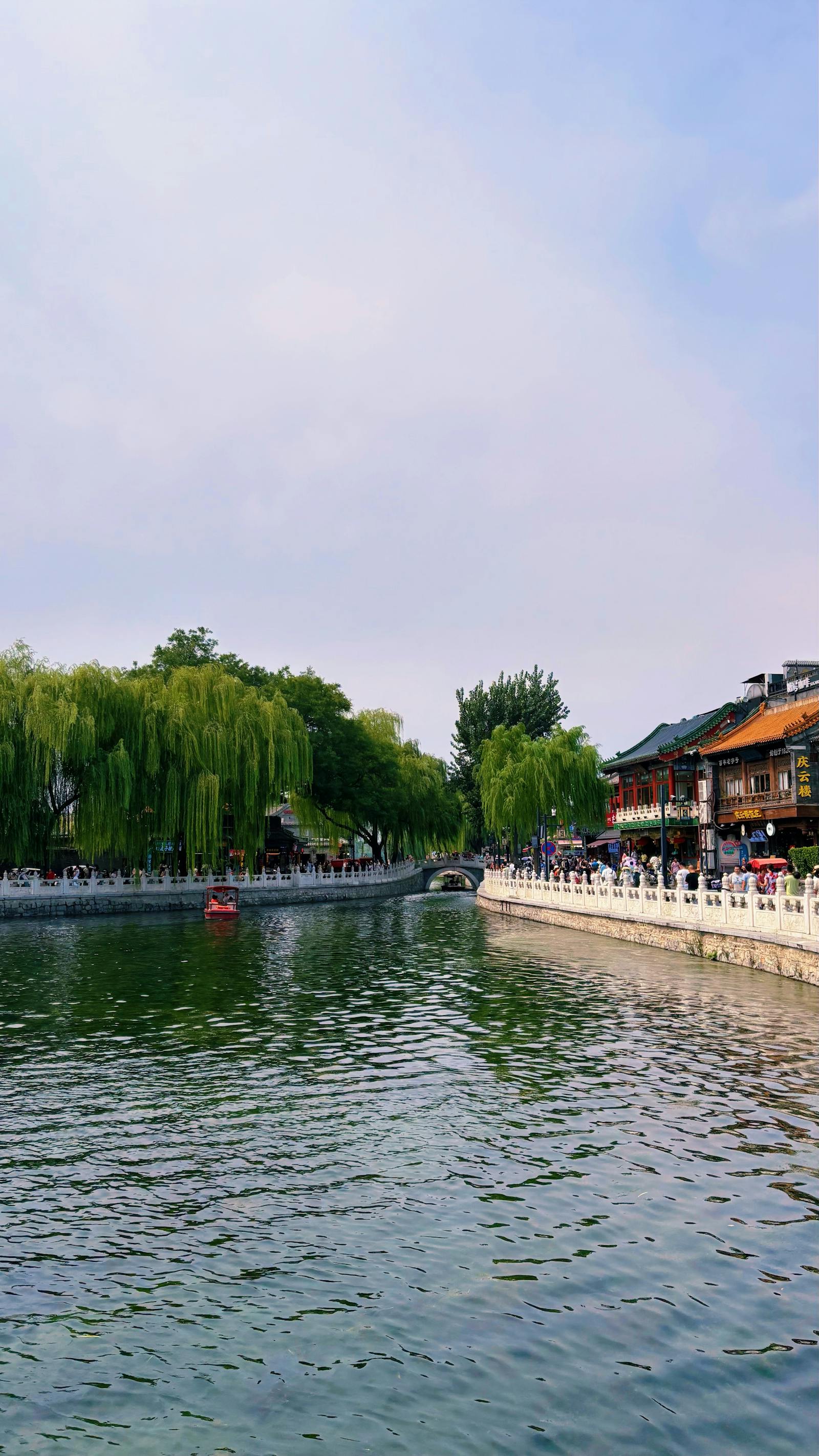 A small paddle boat moored on Houhai Lake with willows along the bank