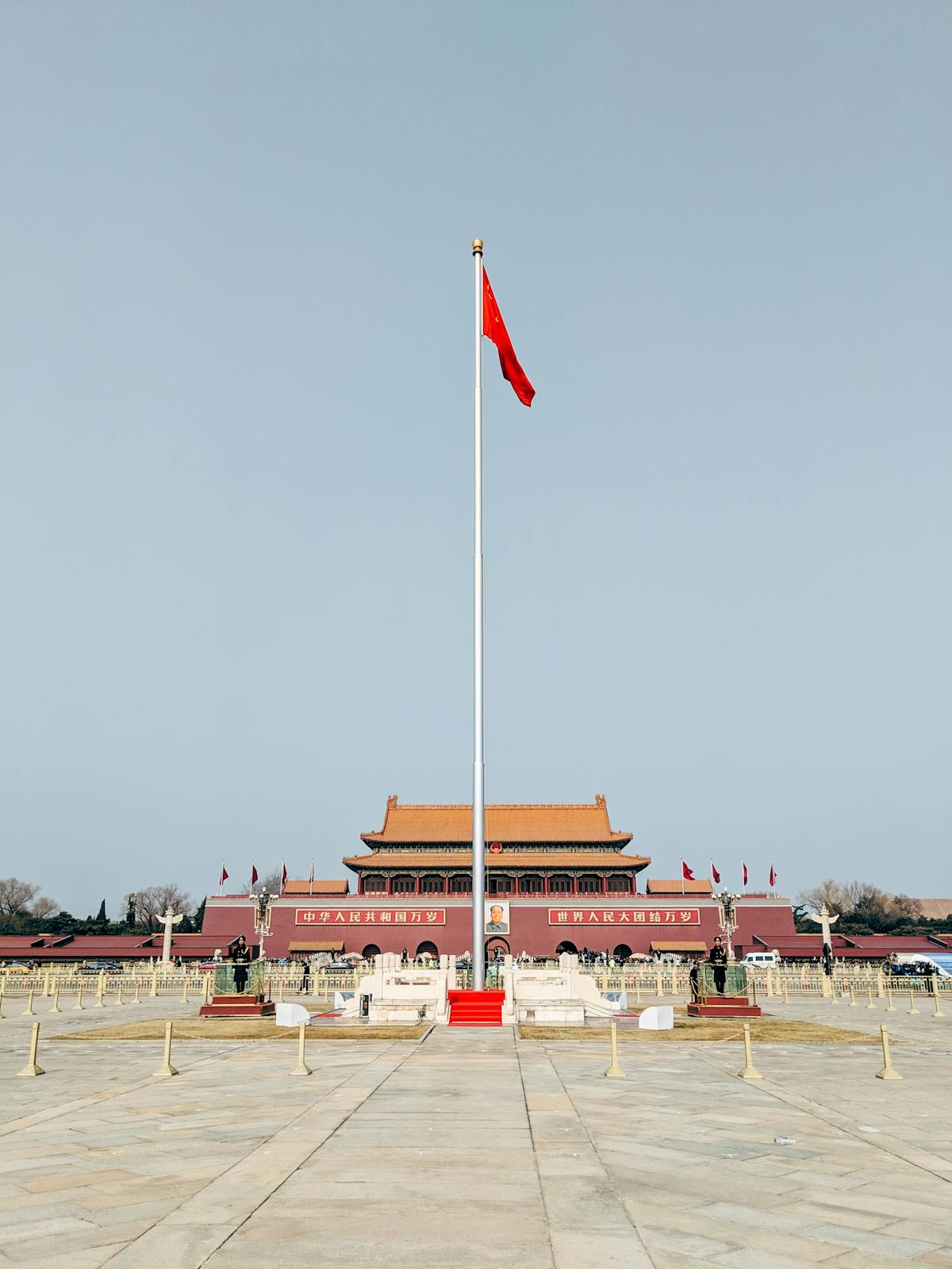 The Chinese flag flying at the northern end of Tiananmen Square at dawn with the gate behind